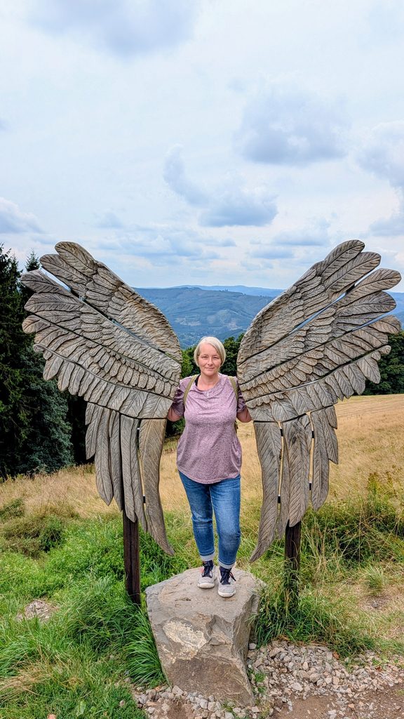 Thora steht zwischen den Flügeln auf dem Naturerlebnisberg in Wildewiese, Sundern.